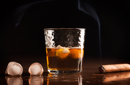 A glass of traditional whiskey and cigar on a wooden table (with copy space)の写真素材