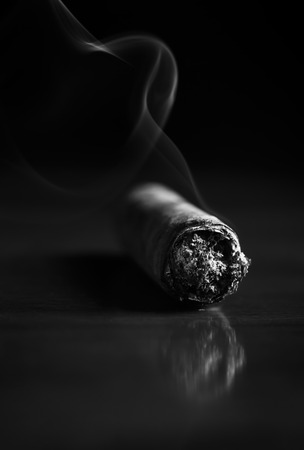 Fuming Havana cigar on a wooden table (b&w)の写真素材