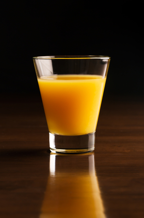 A glass of chilled orange juice on the black wooden backgroundの写真素材