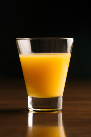 A glass of chilled orange juice on a black backgroundの写真素材