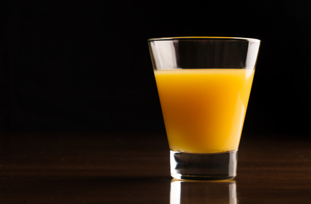 A glass of chilled orange juice on a black backgroundの写真素材