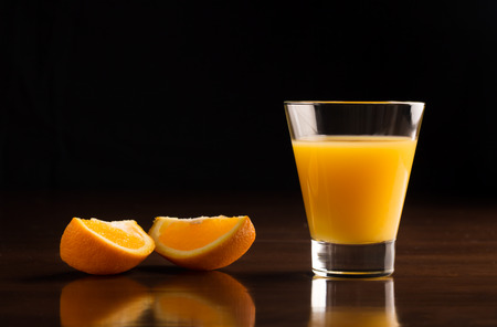 A glass of chilled orange juice on a black backgroundの写真素材