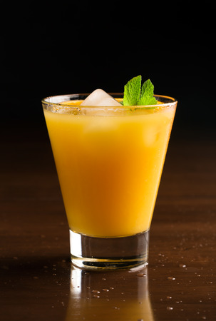 A glass of chilled orange juice on a black backgroundの写真素材
