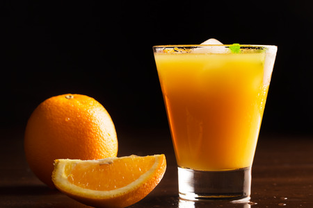 A glass of chilled orange juice on a black backgroundの写真素材