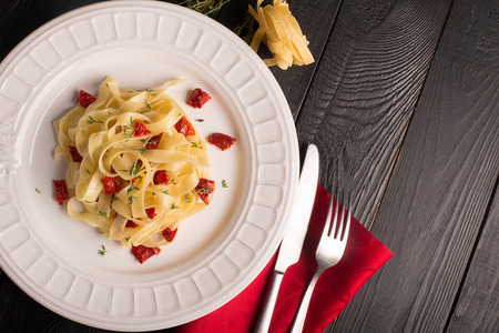 Spaghetti with dried tomatoes on wooden black tableの写真素材