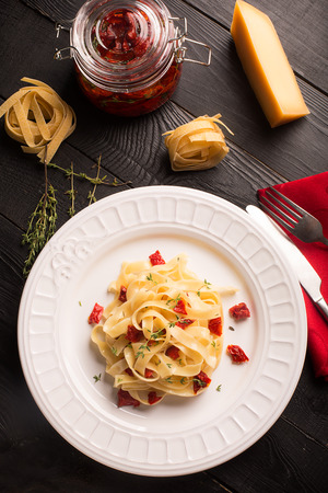 Spaghetti with dried tomatoes on wooden black tableの写真素材