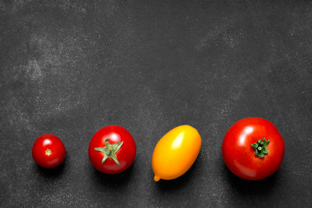 Fresh red and yellow tomatoes on the black chalkboard (copy space for your text or image)の写真素材