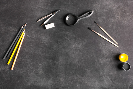 Back to school concept. Compass, magnifying glass, brush, eraser on the black chalkboard. You can...