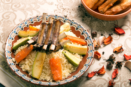Traditional couscous dish with lamb ribs and vegetables. Still life with rose petals on the table. The image is describing moroccan cultureの写真素材