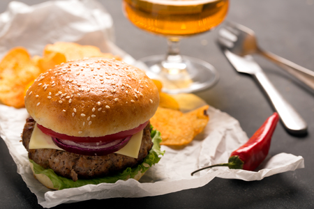 Beef burger with lettuce and minced meat cutlet. Potato chips and glass of beerの写真素材