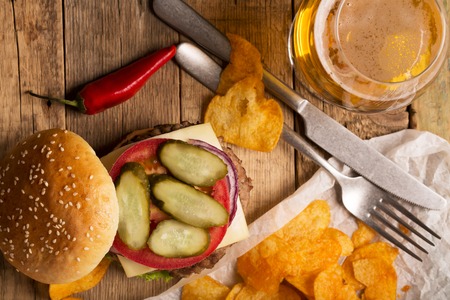 Beef burger with lettuce and minced meat cutlet. Potato chips and glass of beerの写真素材