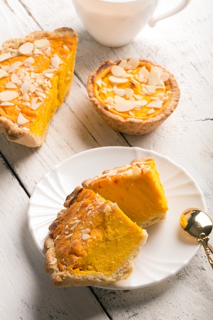 Pumpkin pie with almond slices on white rustic background, verticalの写真素材