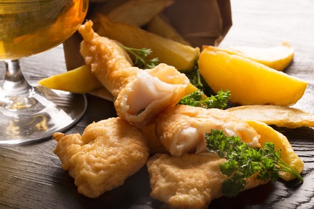 Traditional British fish and chips close up on the black background with glass of beerの写真素材
