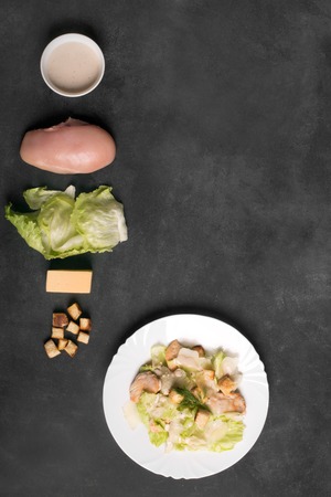 Classical Caesar salad with sliced chicken meat, fresh salad leaves, croutons and sauce in white round plate. Copy space for your textの写真素材