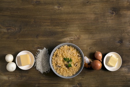 Risotto with mushrooms, fresh herbs and parmesan cheese. Wooden background, top view with copy spaceの写真素材