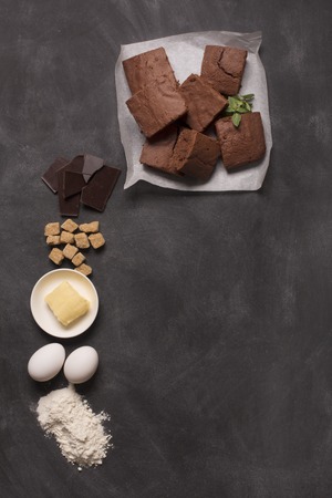 Chocolate brownie cake and ingredients. Top view black chalkboard, copy spaceの写真素材