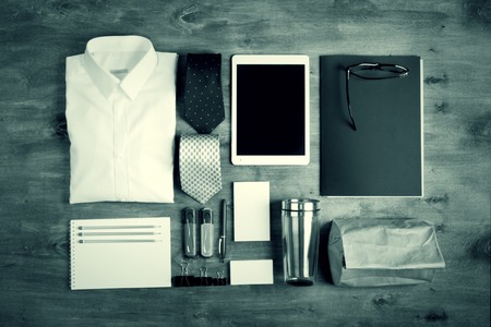 Business objects on the desk,including digital tablet, shirt, ties, lunch box, paper and pencils, top view,monochromeの写真素材