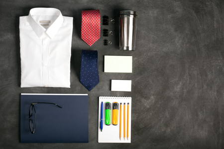 Business objects on the desk,including digital tablet, shirt, ties, lunch box, paper and pencils, on the black chalkboardの写真素材