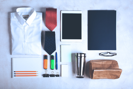 Business objects on the desk,including digital tablet, shirt, ties, lunch box, paper and pencils, top viewの写真素材