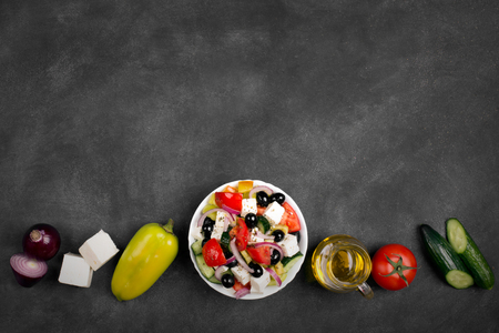 Greek salad ingredients: fresh vegetables, feta cheese and black olives on the chalkboardの写真素材