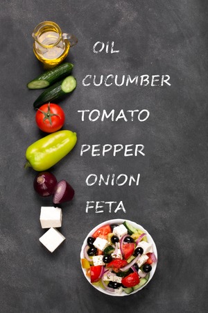 Greek salad ingredients: fresh vegetables, feta cheese and black olives on the black chalkboardの写真素材
