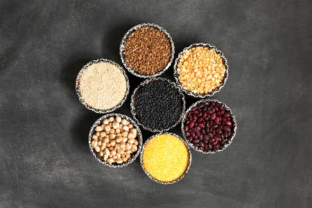 A selection of various colorful cereal on a black chalkboard in bowls. Looks like flowerの写真素材