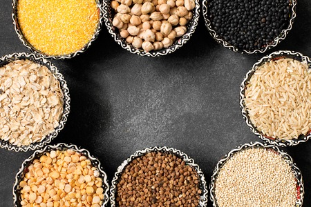 A selection of various colorful cereal on a black chalkboard in bowls. Macro, top viewの写真素材