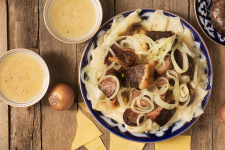 National Kazakh dish - Beshbarmak prepared with meat and pasta on the rustic wooden tableの写真素材