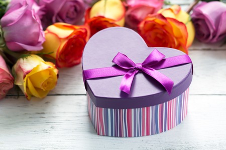 Box present on the forefront, purple and yellow rosesの写真素材