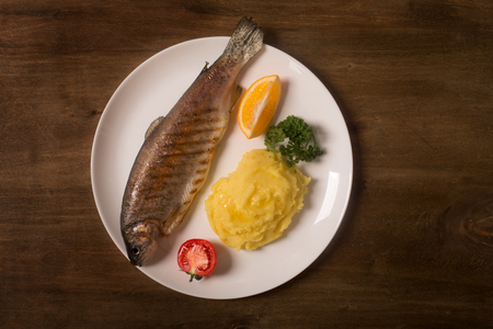 Grilled whole trout, potato, lemon and garlic, close upの写真素材