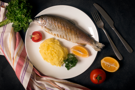 Grilled whole trout, potato, lemon and garlic, close upの写真素材