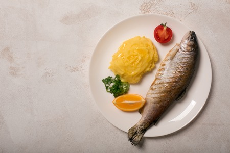 Grilled whole trout, potato, lemon and garlic, close upの写真素材