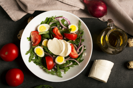Italian salad prepared with arugula, mozzarella, eggs. Black backgroundの写真素材