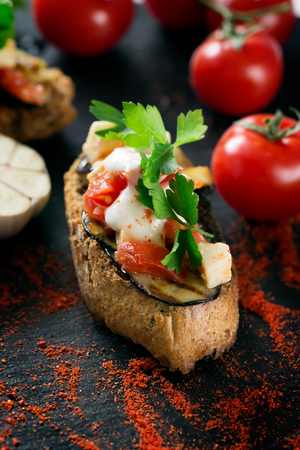 Tasty savory tomato Italian bruschetta, on slices of toasted baguette garnished with parsley and eggplantの写真素材