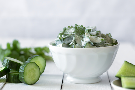 Cucumber salad with yogurt dressing on the white backgroundの写真素材