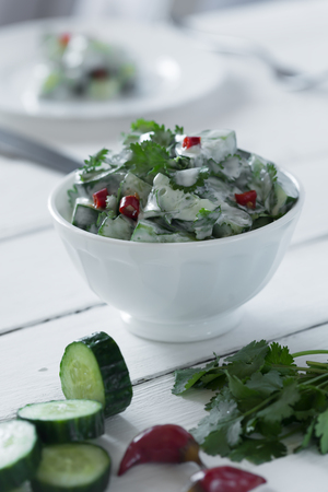 Cucumber salad with yogurt dressing on the white backgroundの写真素材