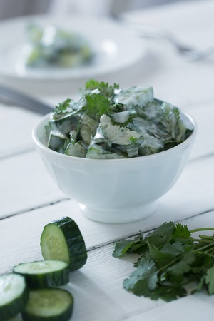 Cucumber salad with yogurt dressing on the white background. Vertical orientationの写真素材