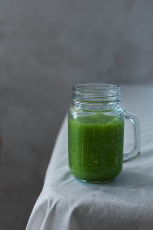 Fresh organic green smoothie with spinach, cucumber on a white tableclothの写真素材