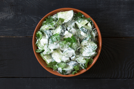 Cucumber salad with yogurt dressing on the black wooden backgroundの写真素材