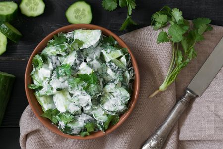 Cucumber salad with yogurt dressing on the black wooden backgroundの写真素材