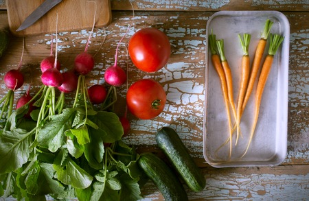Fresh farm vegetables - radish, carrot, cucumber and tomato on old wooden rustic background top view border, place for text. Toned pictureの写真素材