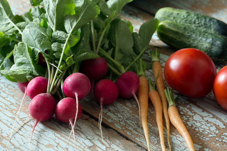 Fresh farm vegetable- radish, cucumber, tomato, carrot on wooden rustic background, side viewの写真素材