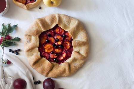 Traditional rustic cake prepared from dough, plum and cherry on the white tablecloth with copy spaceの写真素材