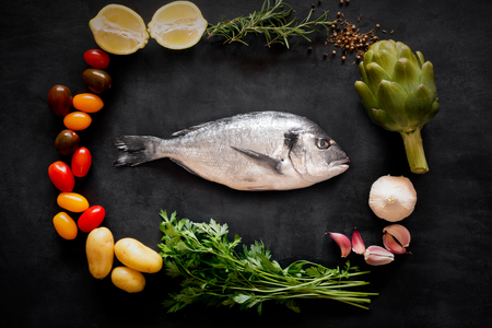 Mediterranean fish - dorado and vegetables on the chalkboard. top viewの写真素材