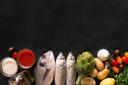 Mediterranean fish - dorado and vegetables on the chalkboard. top viewの写真素材