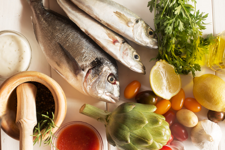 Fresh organic food natural sea fish and veggies on the wooden surfaceの写真素材