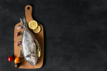 Mediterranean fish - dorado and vegetables on the cutting board. Top view.の写真素材