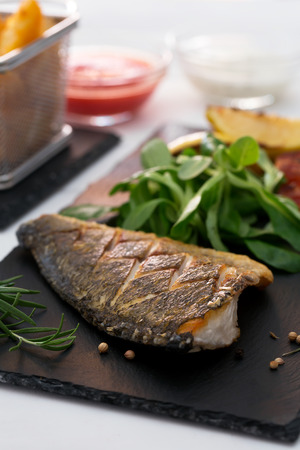 Baked dorado with fresh salad and vegetables. Vertical orientationの写真素材