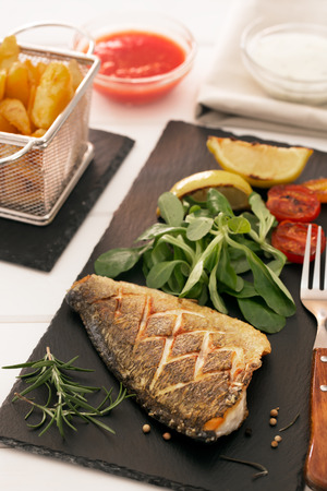 Baked dorado with fresh salad, herbs and vegetables. Vertical orientationの写真素材