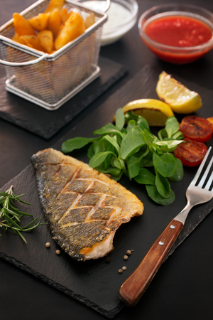 Baked dorado with fresh salad and vegetables. Vertical orientationの写真素材